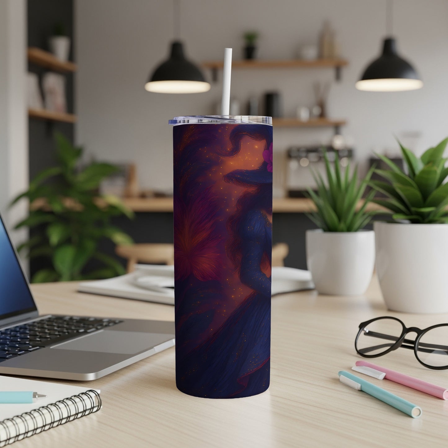 Dark blue tumbler with witch illustration on desk with laptop and plants.
