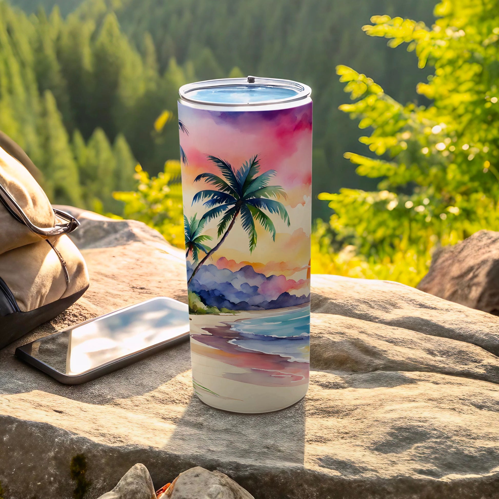 Palm tree beach sunset design on a white tumbler next to a phone.