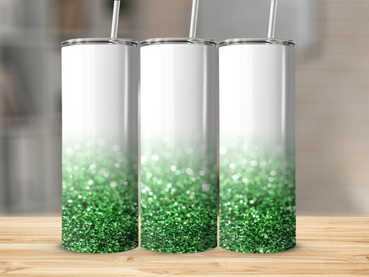 Three white tumblers with green glitter gradient and straw on wooden surface.