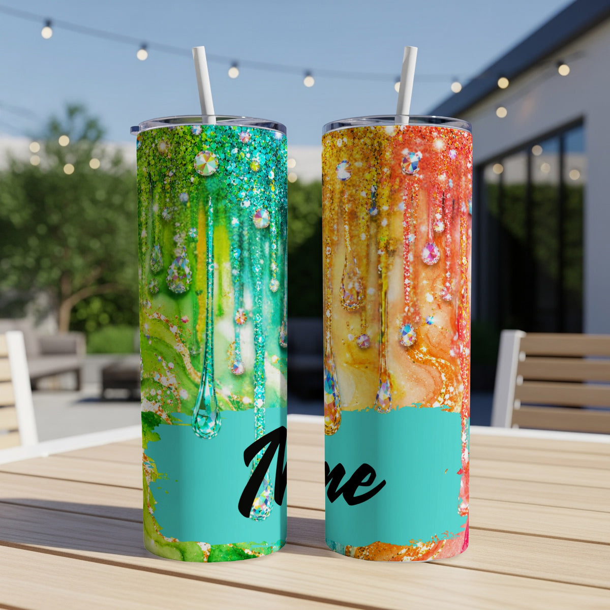 Two tumblers with dripping jewel designs, one green, one orange, on a table.
