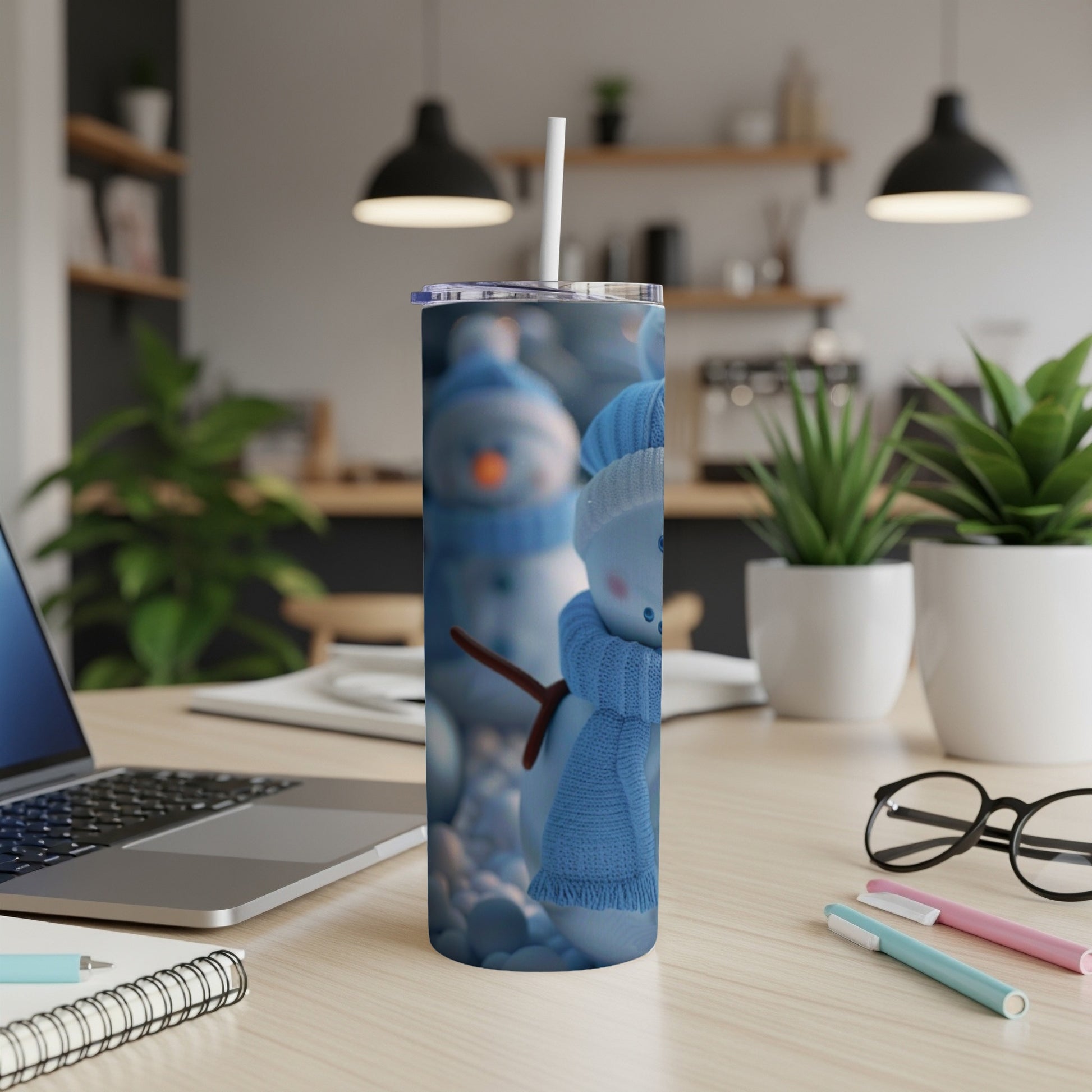 Snowman tumbler with blue scarf and hat, on a desk.