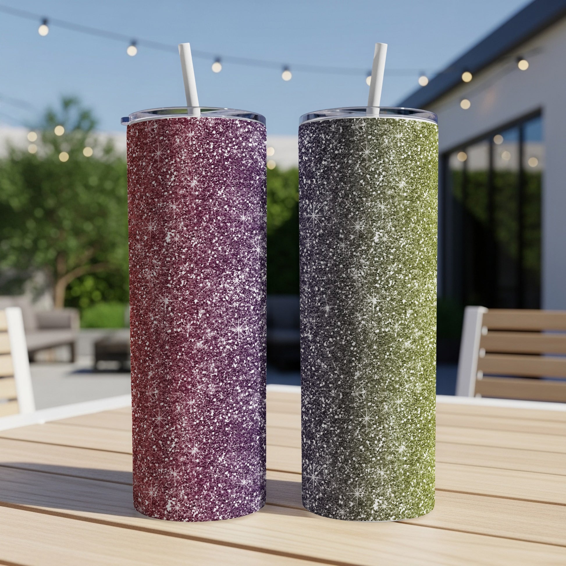Two glitter tumblers, one purple and one green, with white straws sit on a wooden table.