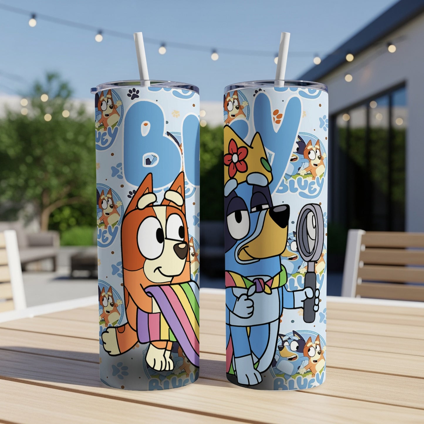 Bluey and Bingo characters on a blue tumbler with a straw, outside.