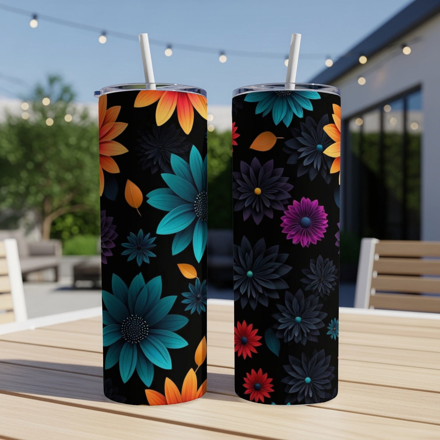 Two black tumblers with colorful floral patterns and straws on a table.
