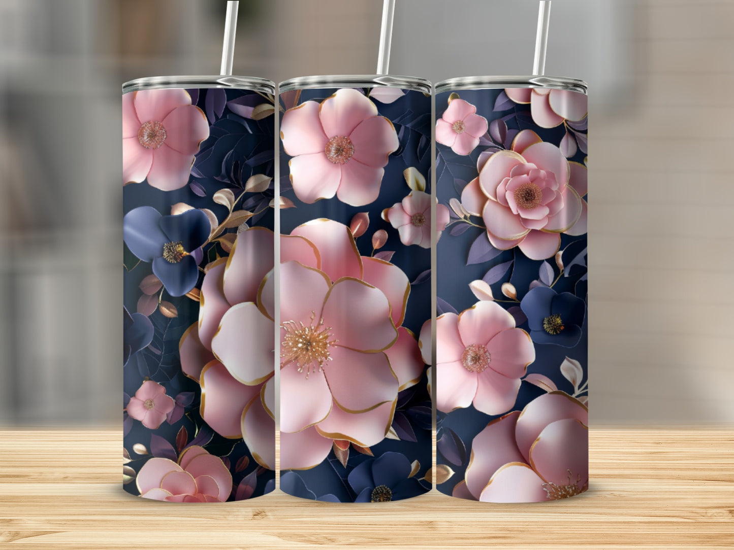 Three pink and blue floral tumblers with straws on a wooden surface.