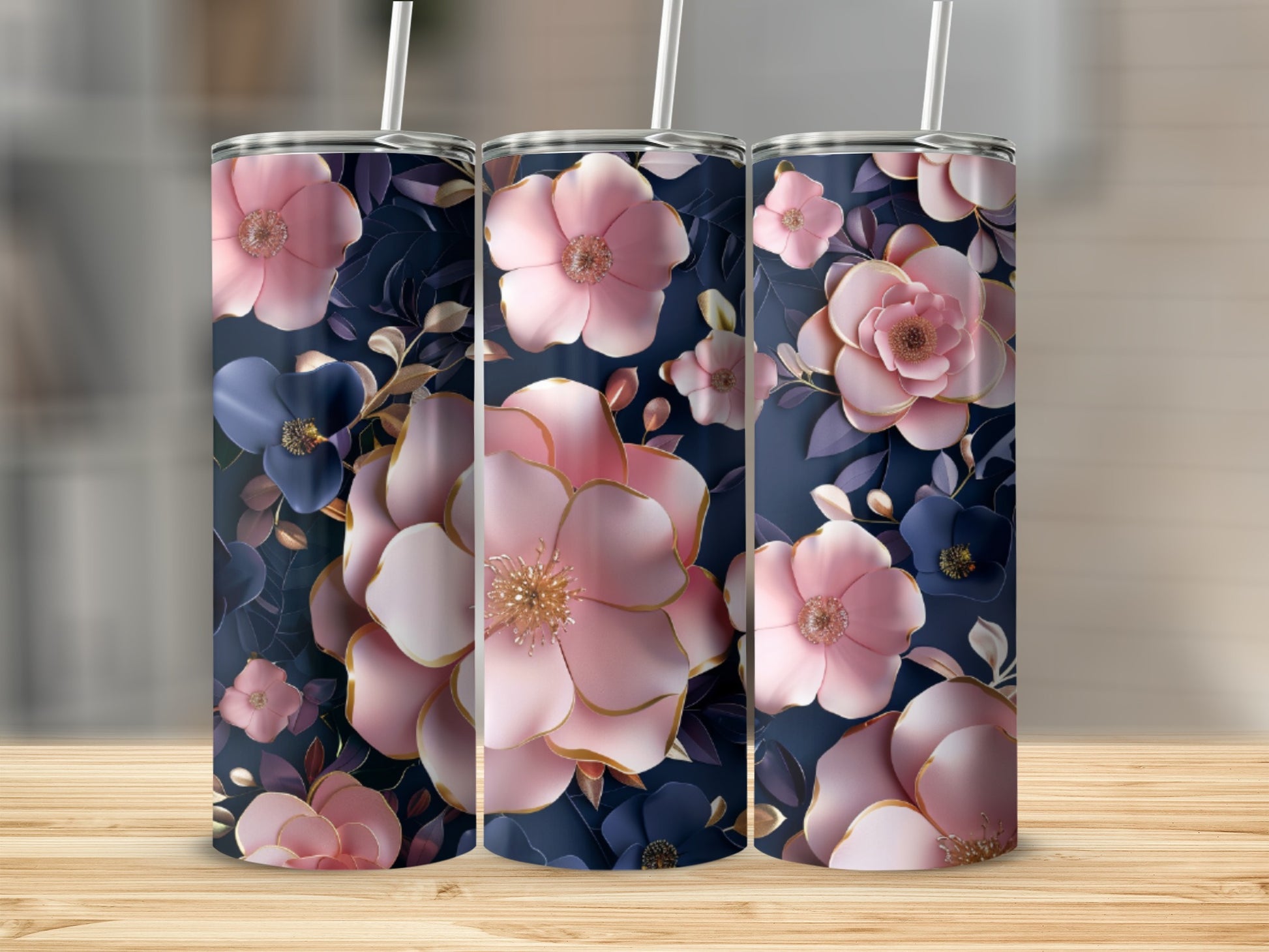 Three pink and blue floral tumblers with straws on a wooden surface.