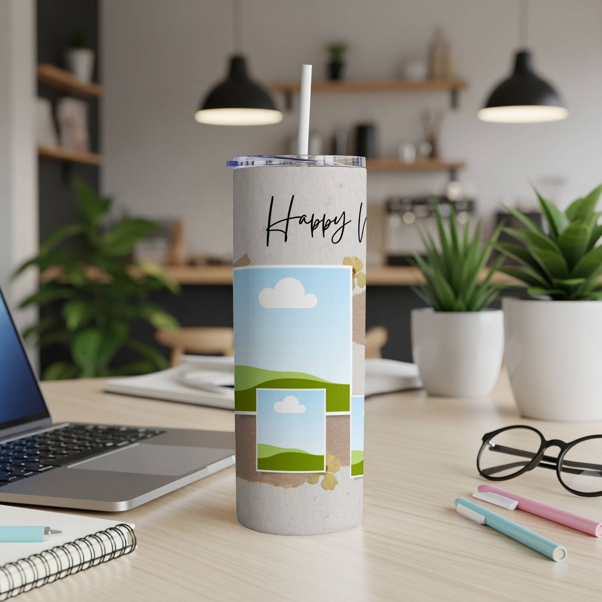 Tumbler with "Happy V" text and layered landscape photo collage on desk.