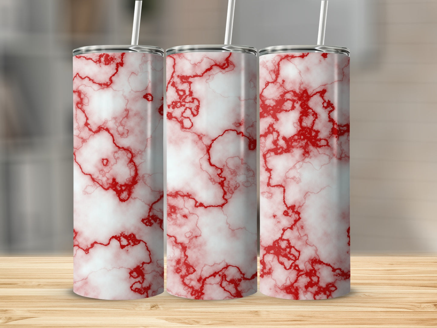Three white tumblers with red marble pattern and straws on a wooden surface.