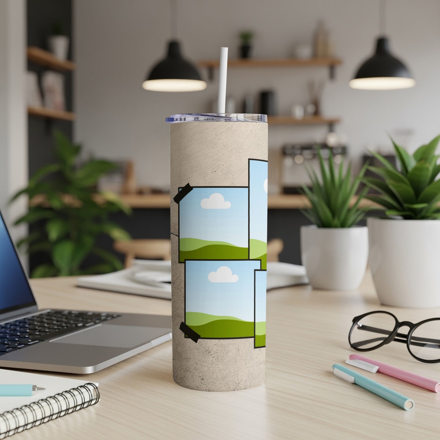 Beige tumbler with tape-adhered landscape photos and a straw on a desk.