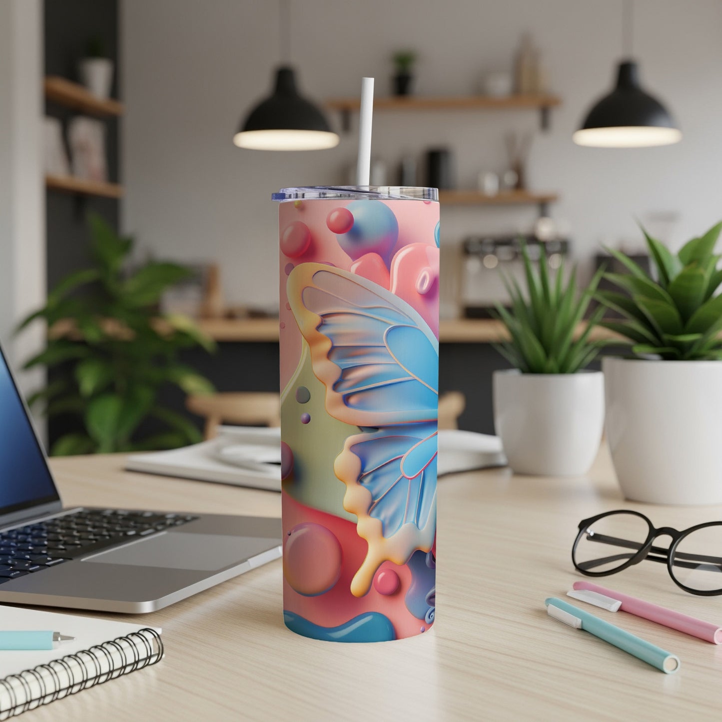Colorful abstract butterfly tumbler with a straw on a wooden desk.