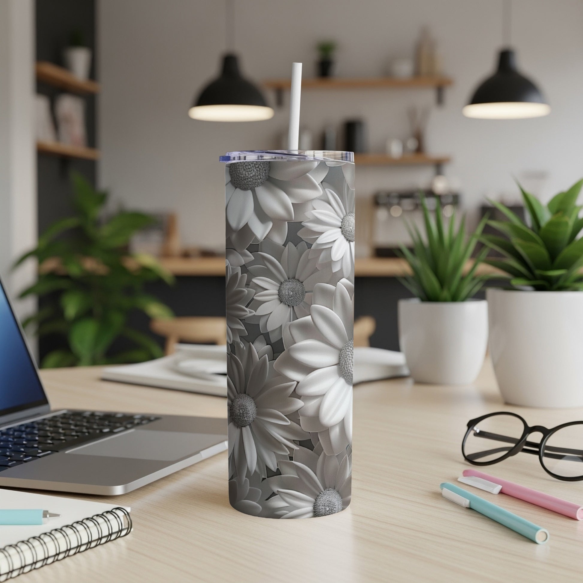 Gray floral pattern tumbler with a straw on a desk.