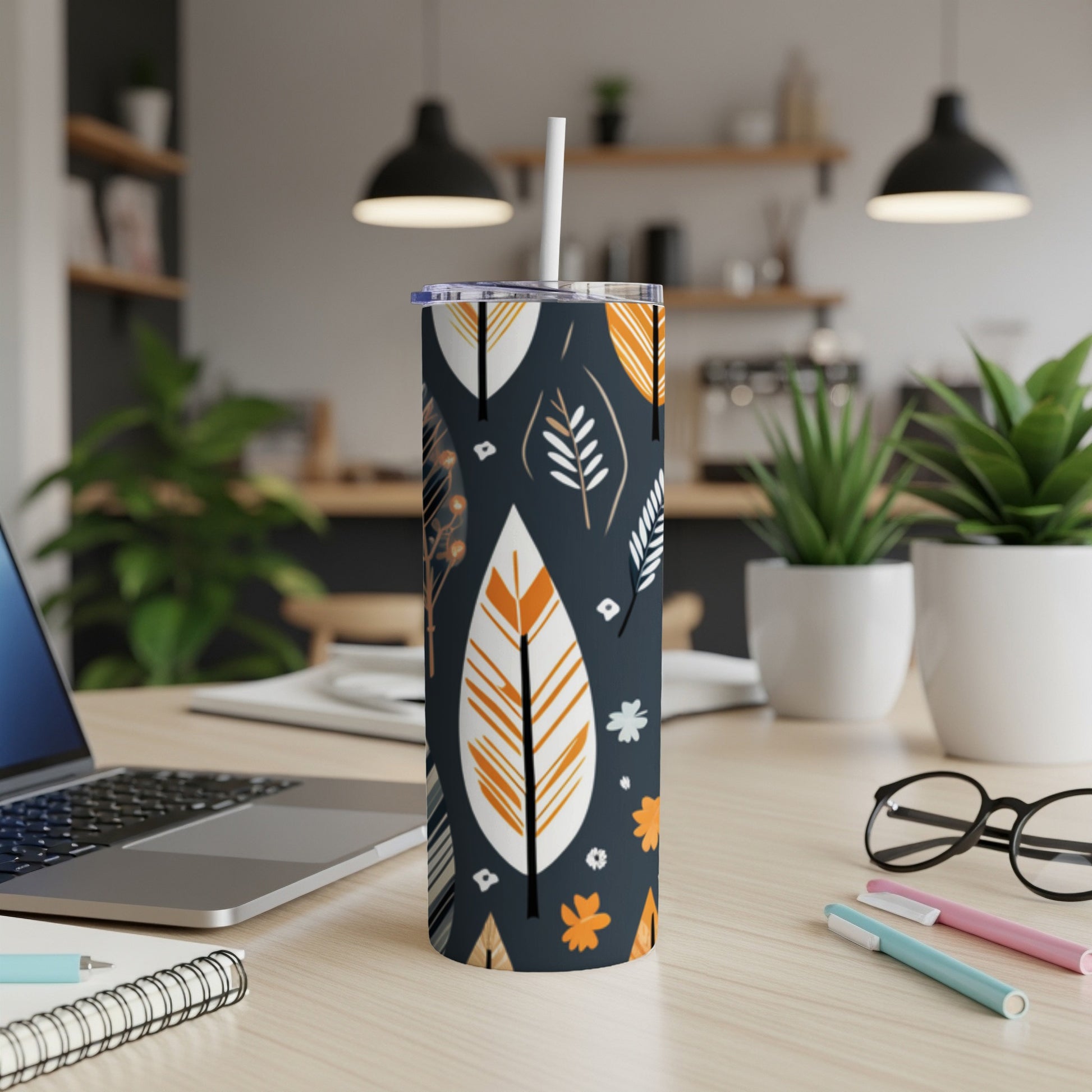 Dark tumbler with white straw featuring a repeating pattern of orange and white leaves.