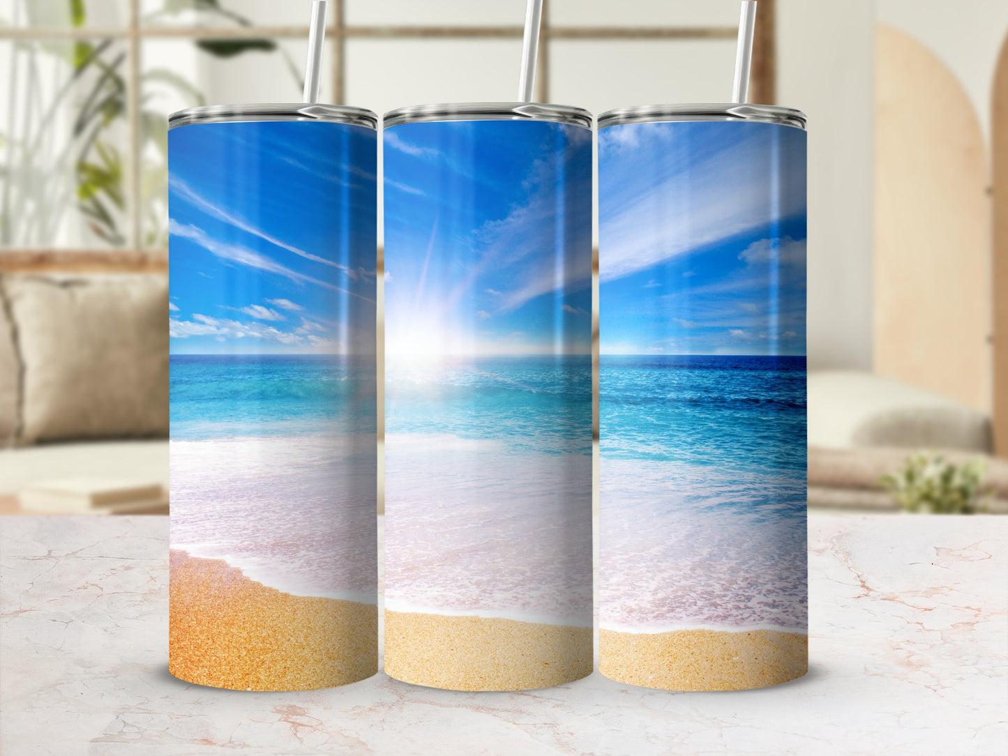Three tumblers with beach scene design, sun glare on ocean.