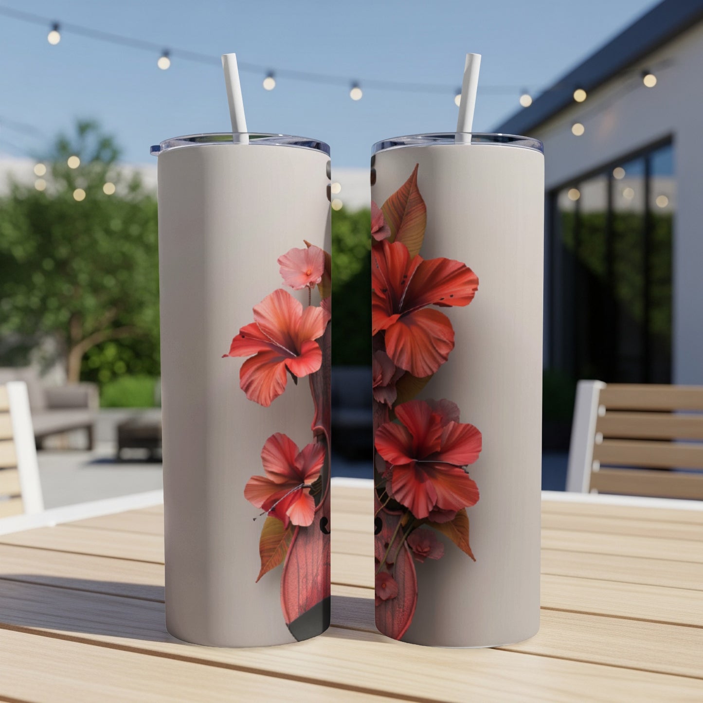 Two tumblers with a hibiscus floral design on a patio table.