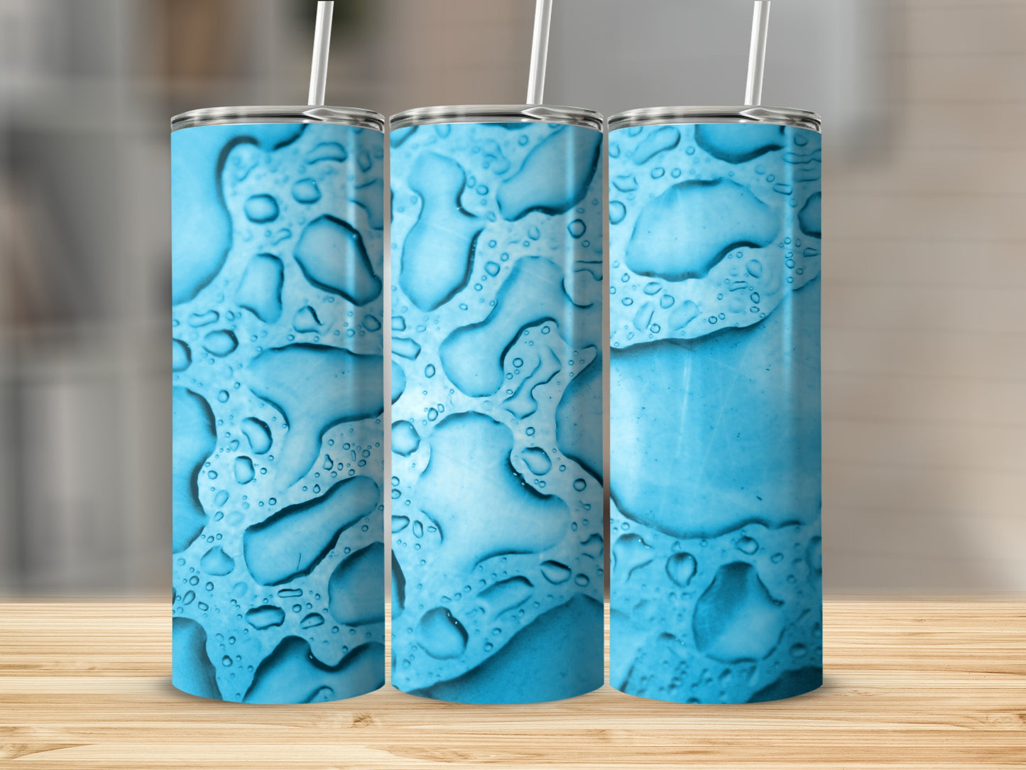 Three tumblers with a blue water drop design stand on a wooden surface.