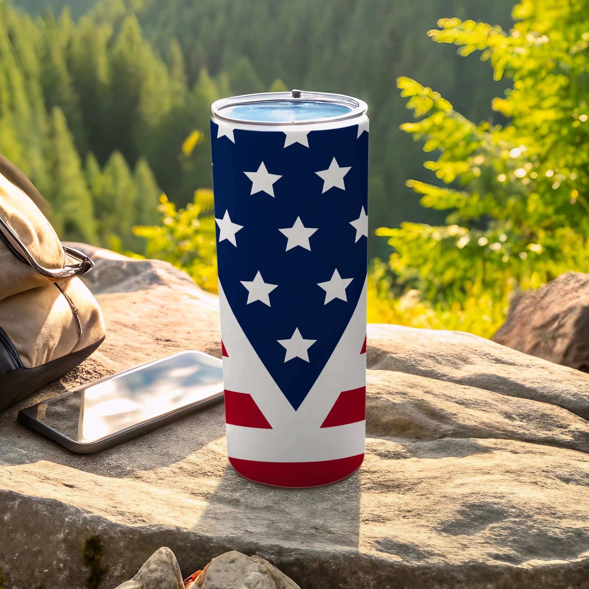 American flag tumbler on a rock with a backpack and phone.