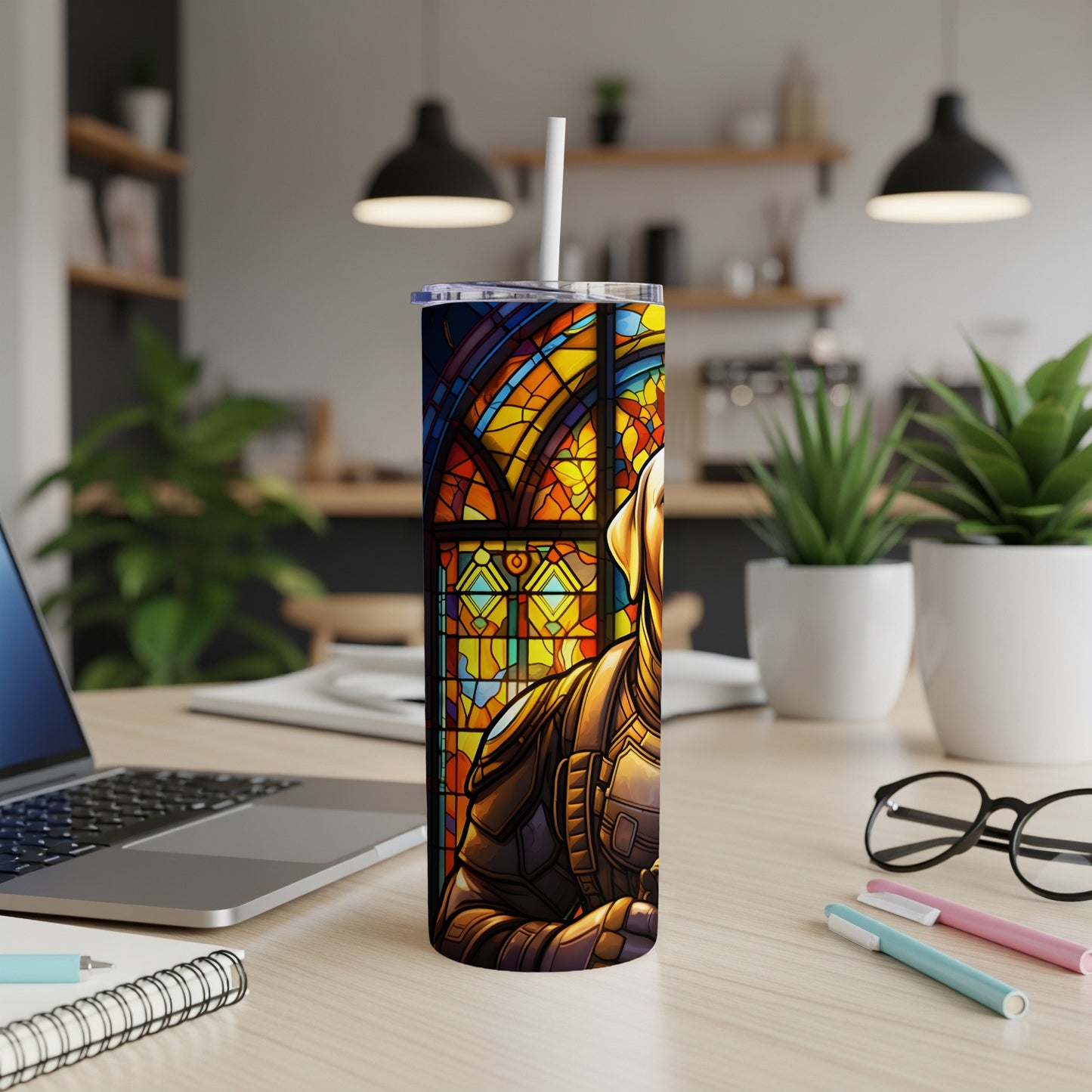 Tall tumbler with stained glass knight design on desk with laptop and plants.