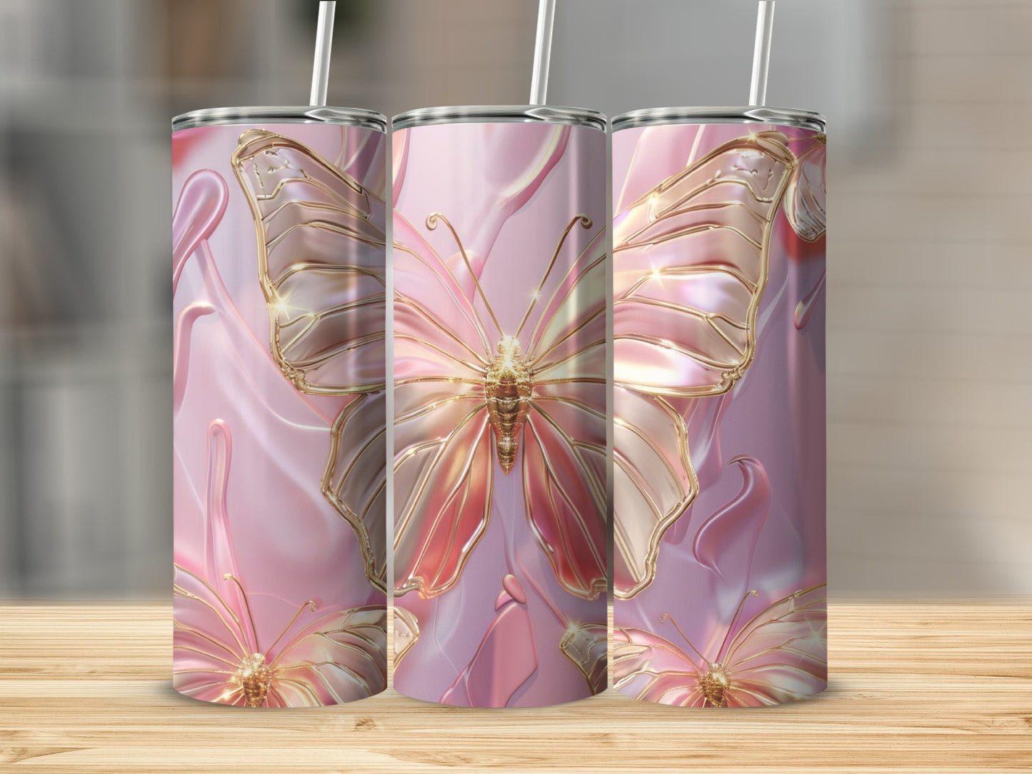 Three pink iridescent tumblers with golden butterfly designs on a wooden surface.