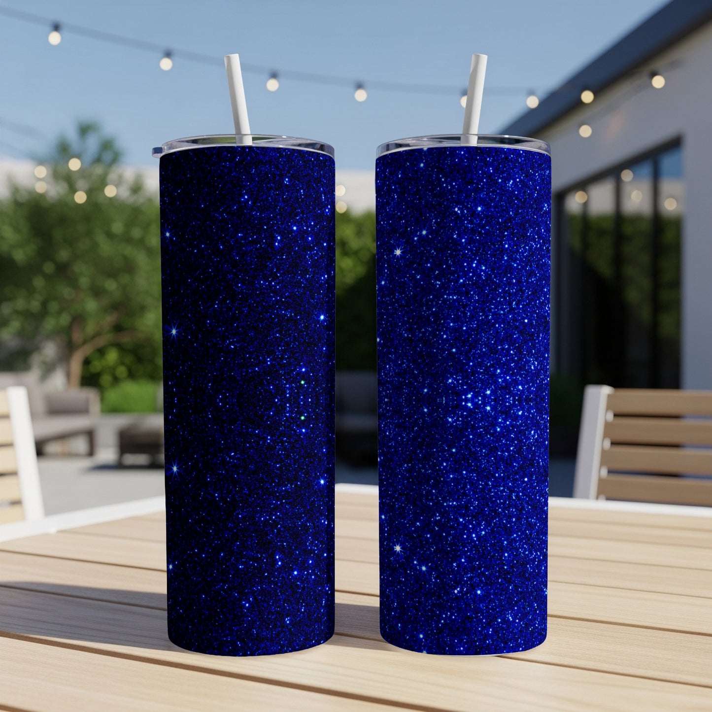 Two blue glitter tumblers with white straws on a wooden table.