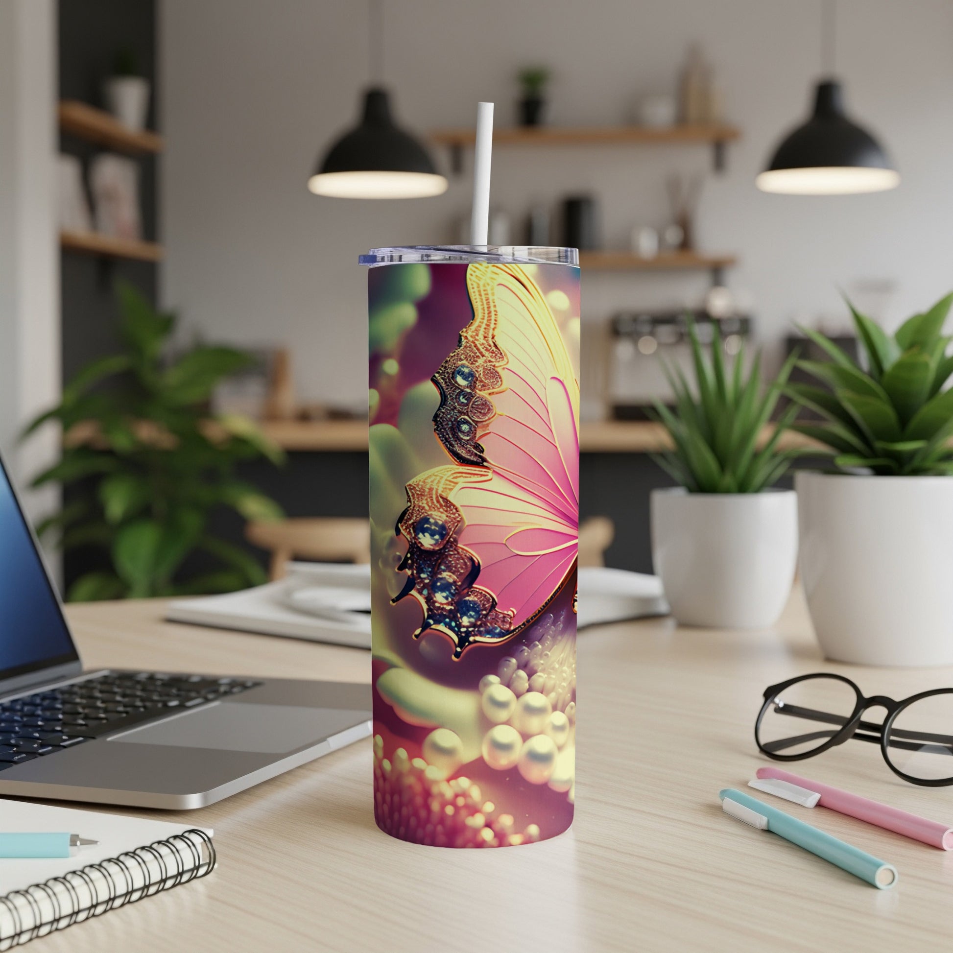 Pink butterfly design on a white tumbler with a straw, on a desk.