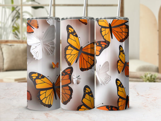 Three tumblers decorated with orange and white butterflies on a textured surface.