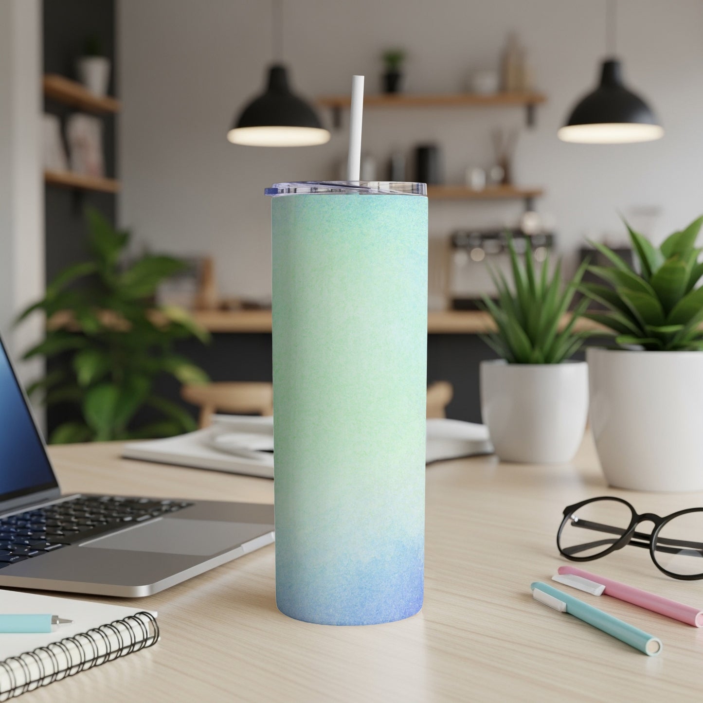 Blue and green gradient 20 oz tumbler with straw on a desk.