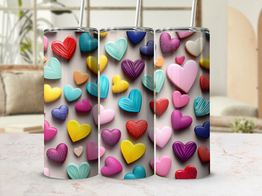 Three colorful heart-patterned tumblers with straws, arranged in a row.