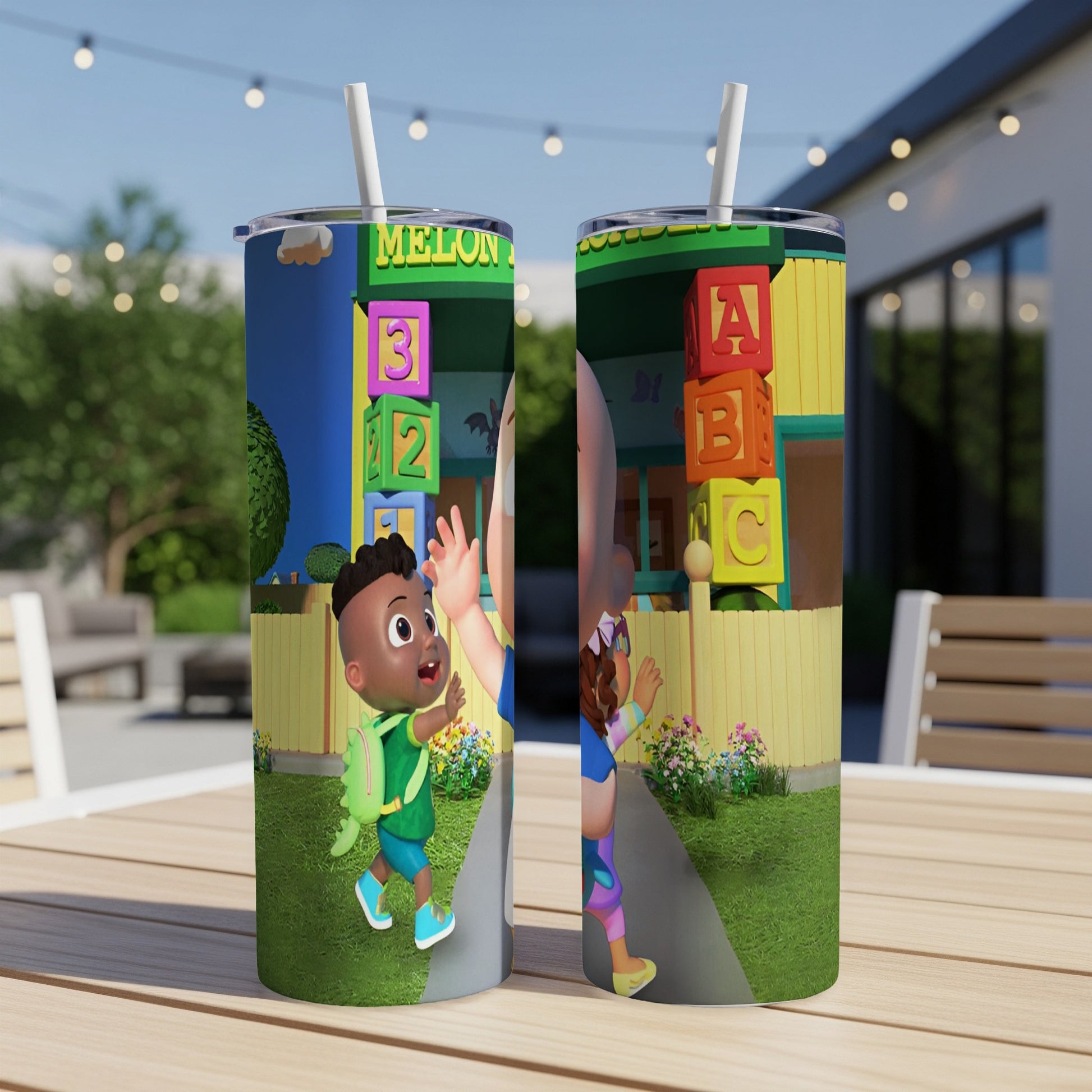 Tumbler with cartoon children and colorful ABC blocks in a backyard setting.