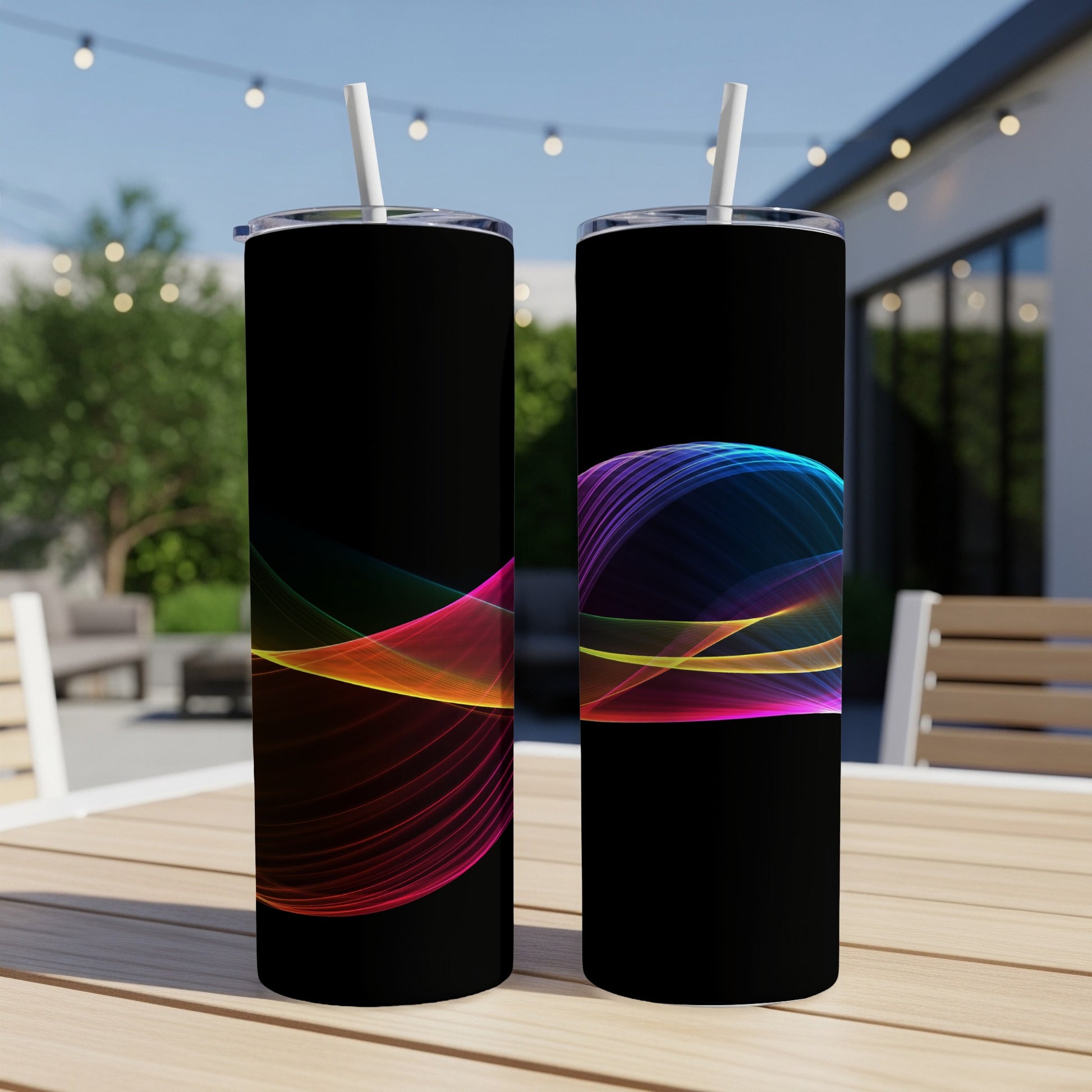 Two black tumblers with colorful abstract wave designs sit on a wooden table.