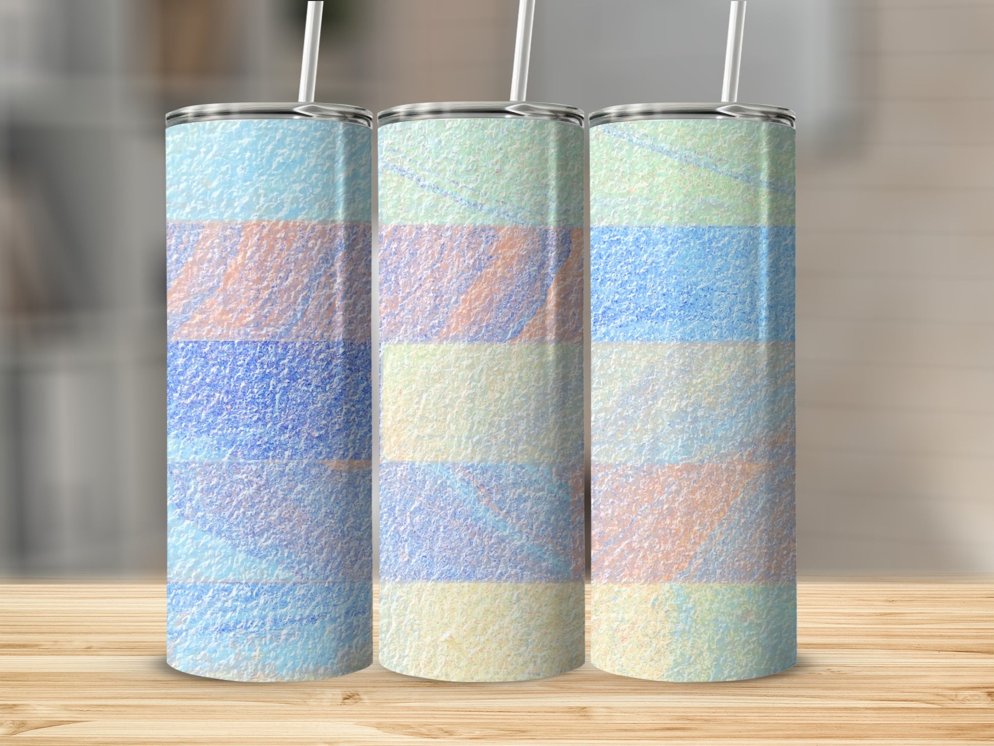 Three tumblers with pastel watercolor stripes and straws, on a wooden surface.