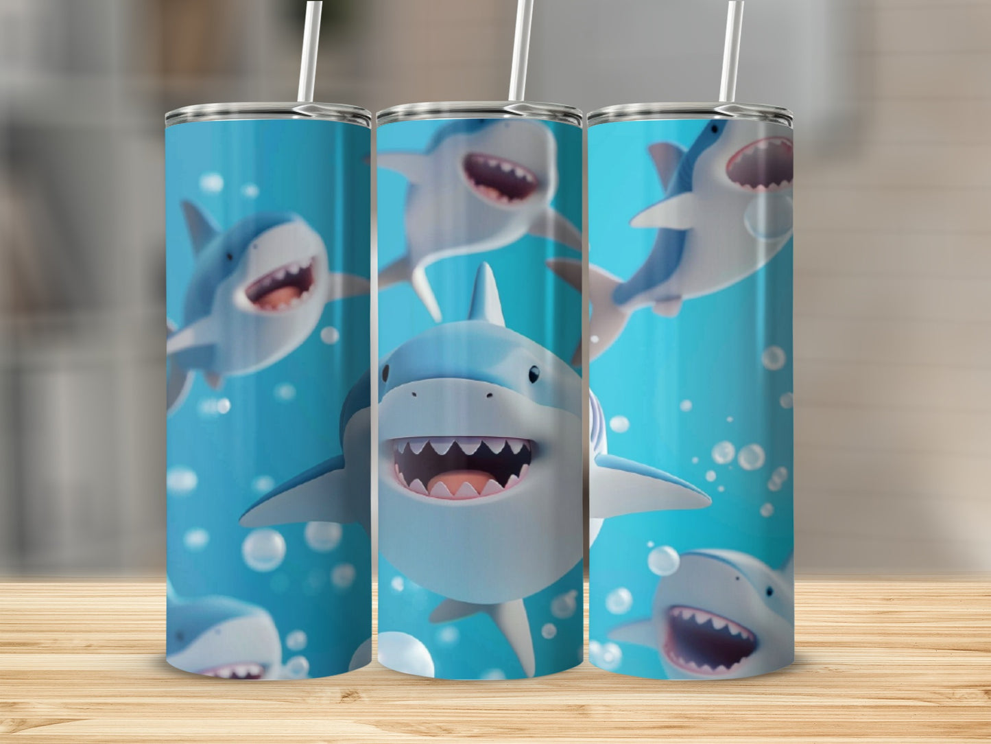 Three cartoon shark tumblers with straws on a wooden surface.