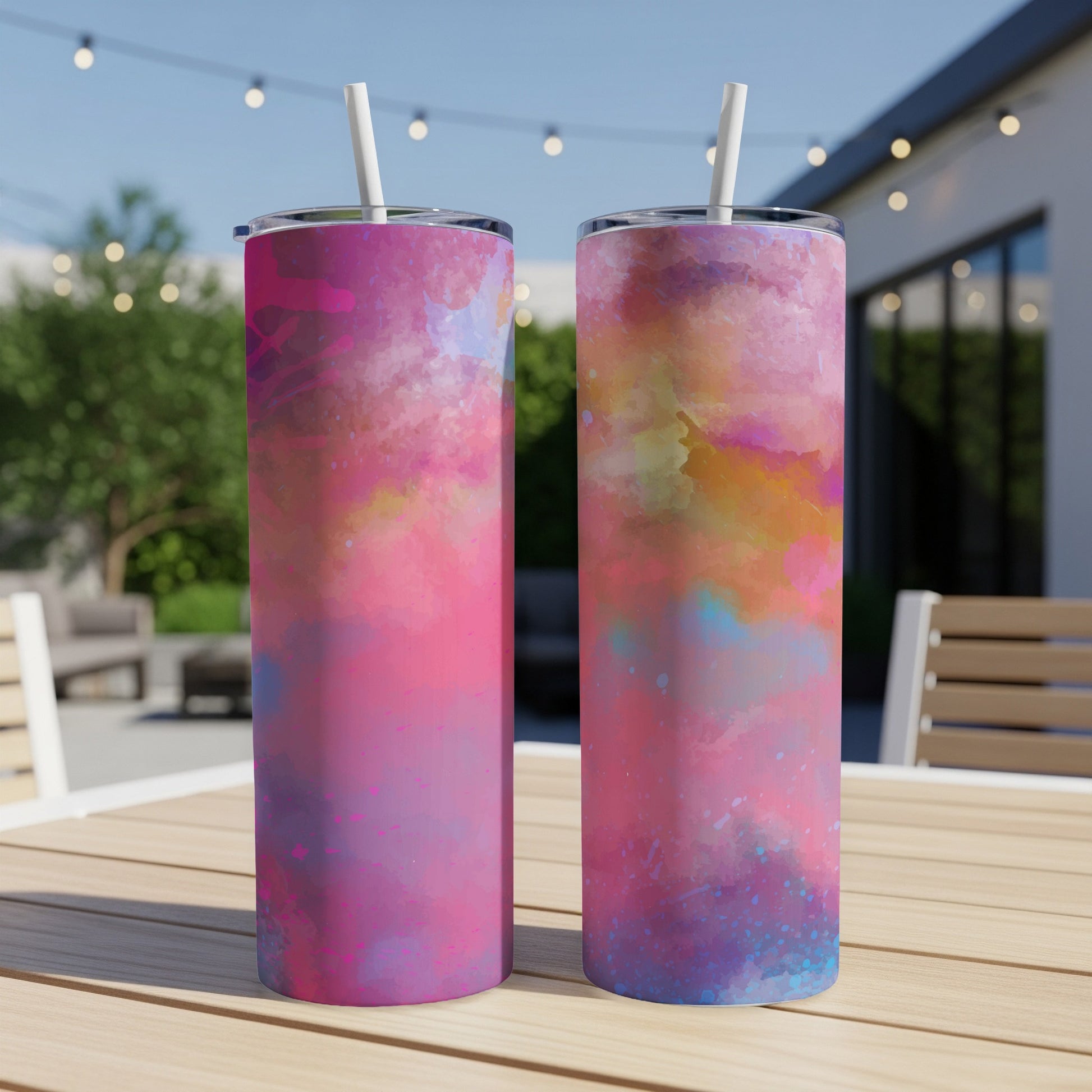Two tumblers with pink, purple, and blue watercolor abstract designs with white straws.