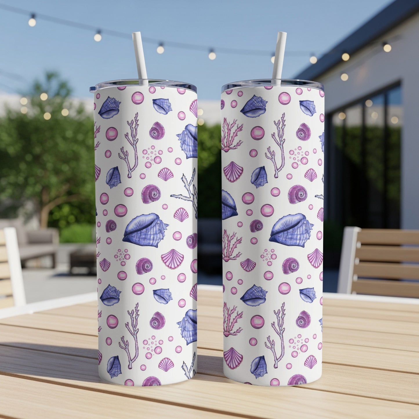 Two tumblers with seashell and coral pattern on a table.