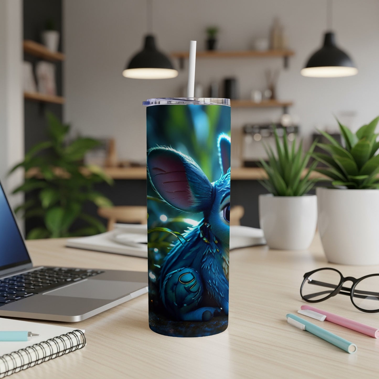 Blue creature with big ears on a tumbler with a laptop and plants.