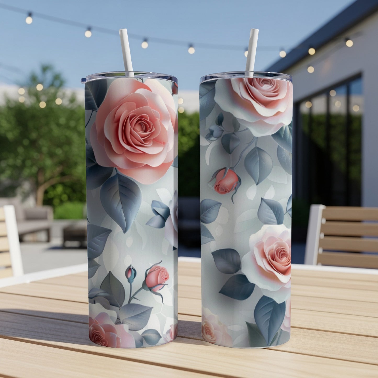 Two tumblers with a pink and white rose floral pattern on a wooden table outdoors.