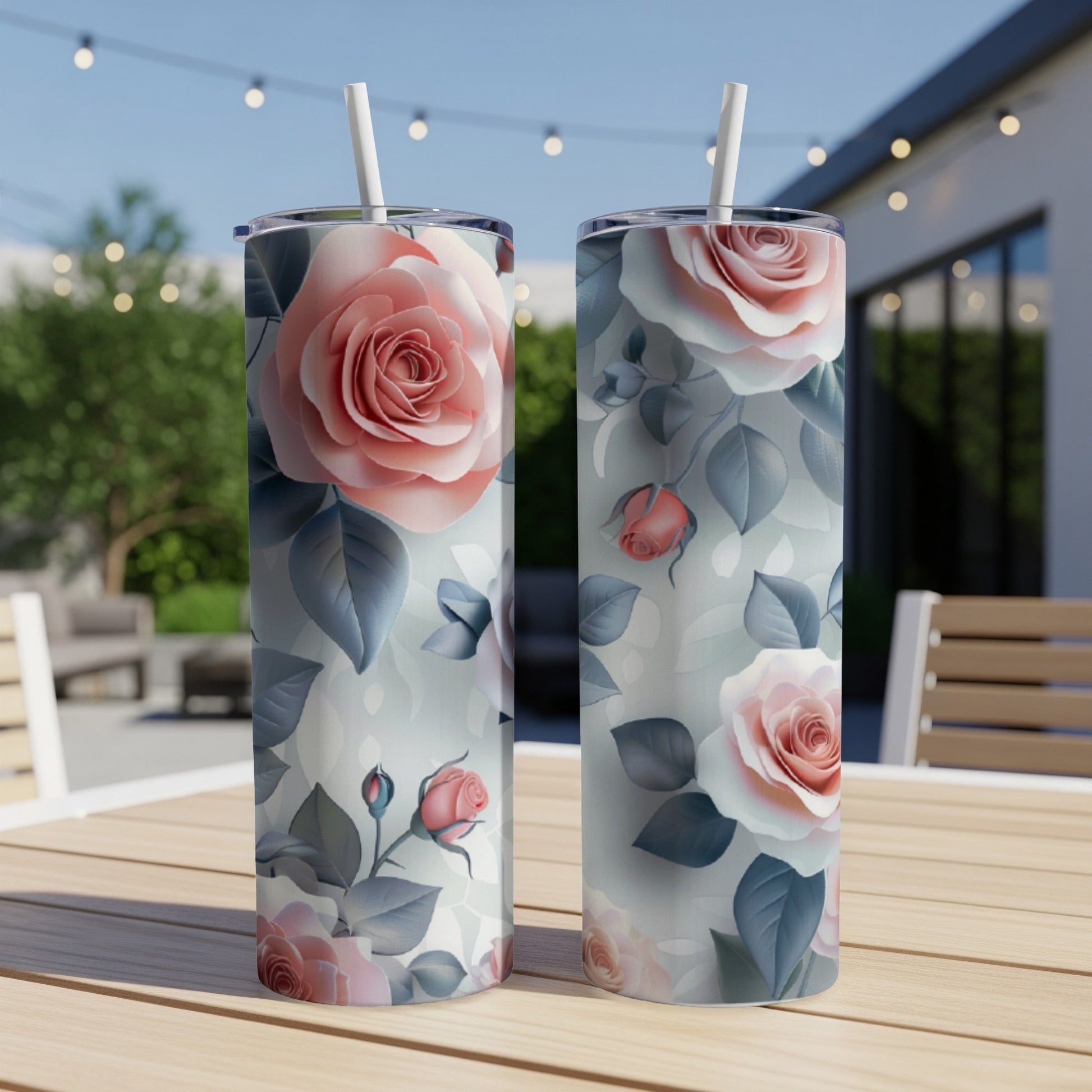 Two tumblers with a pink and white rose floral pattern on a wooden table outdoors.