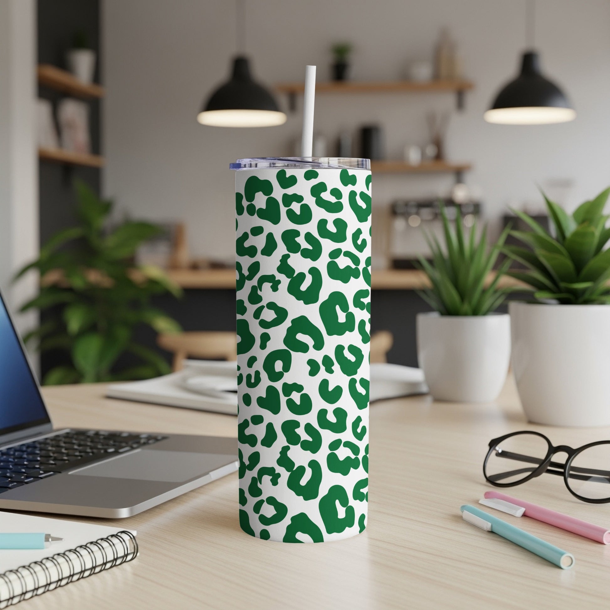 Green leopard print tumbler with white straw on a desk.