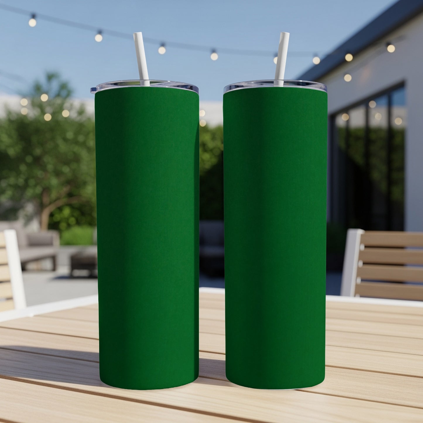 Two tall, green tumblers with white straws sit on a wooden table outdoors.