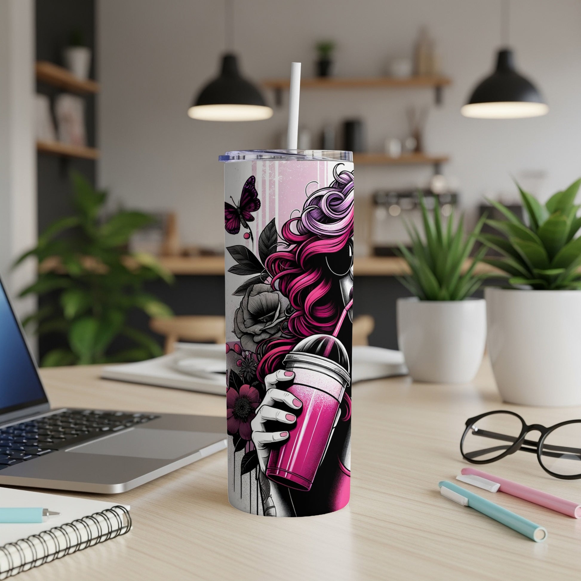 Pink tumbler with woman's silhouette and flowers, on desk with laptop.