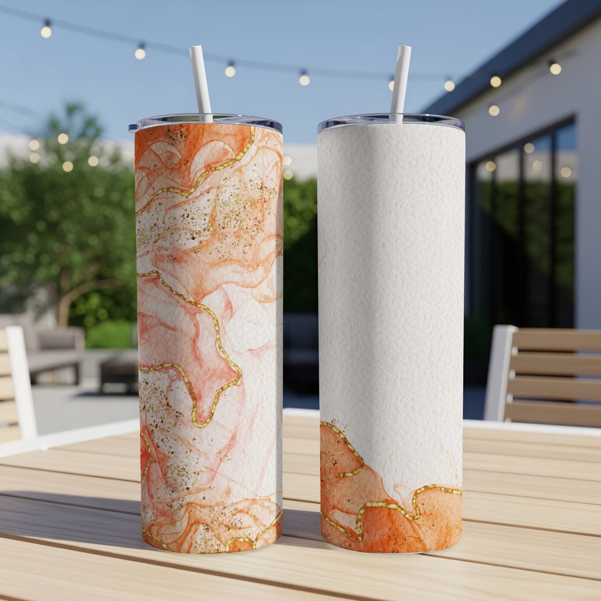 Two tumblers with marble and gold accents displayed on a table outdoors.
