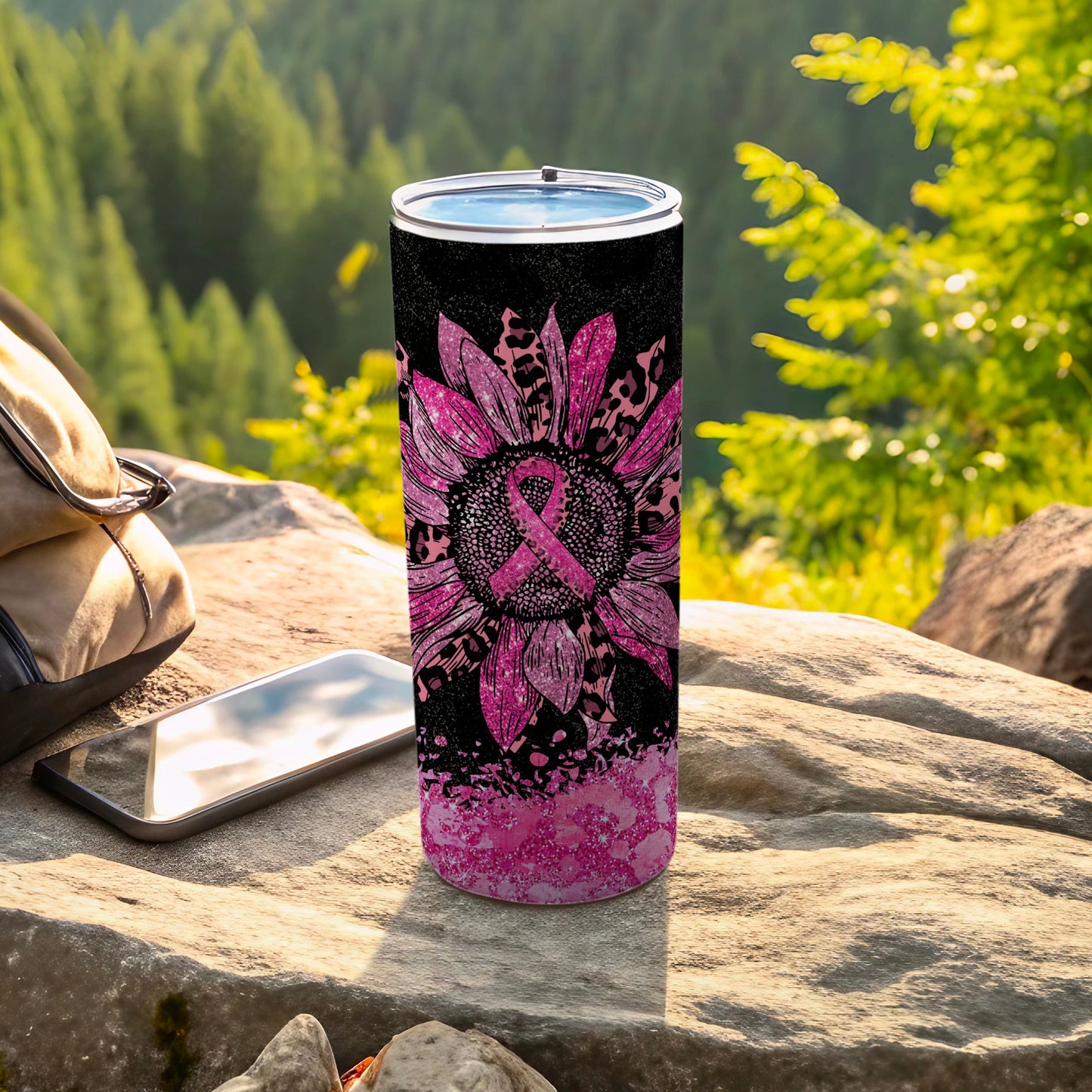 Pink sunflower and leopard print tumbler on rocks with forest background.