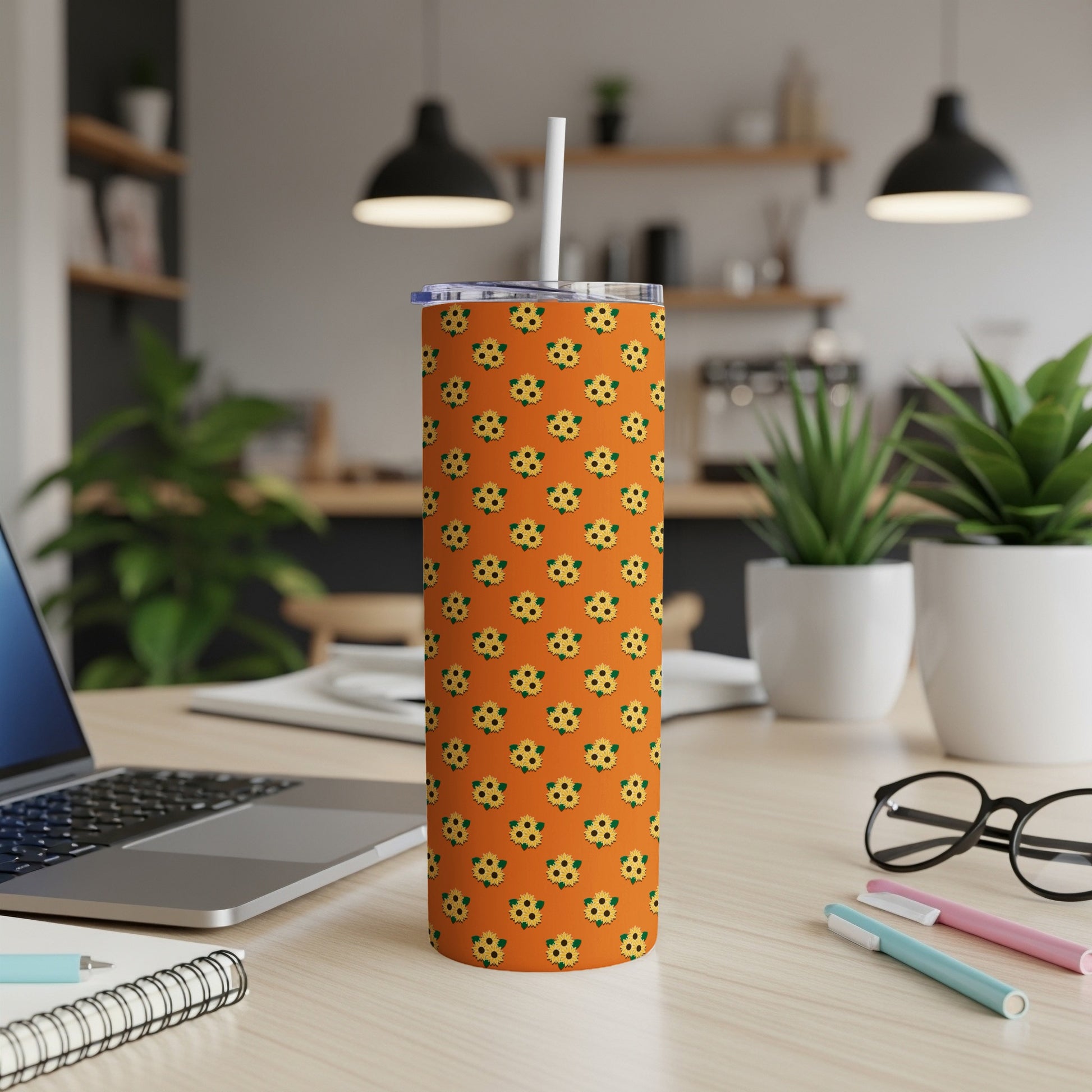 Orange tumbler with repeating sunflower pattern and white straw.