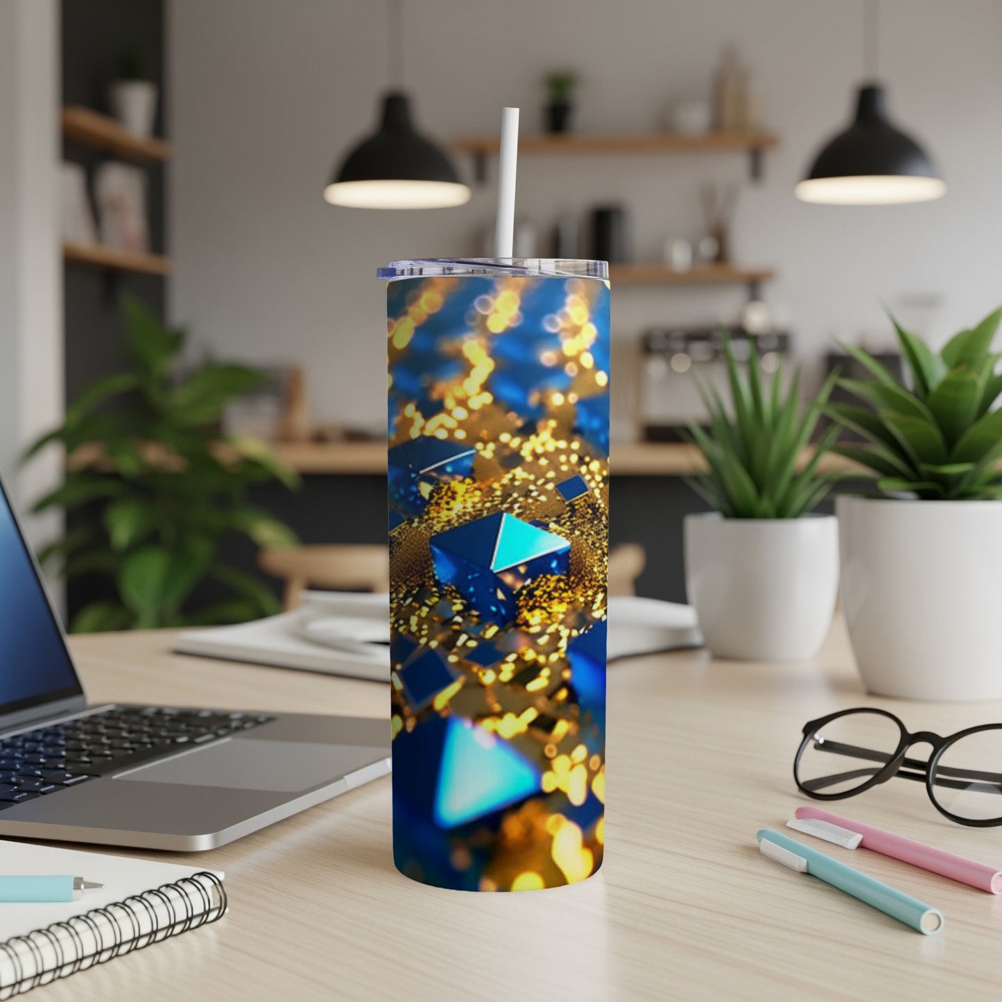 Blue geometric pattern tumbler with straw on a desk.
