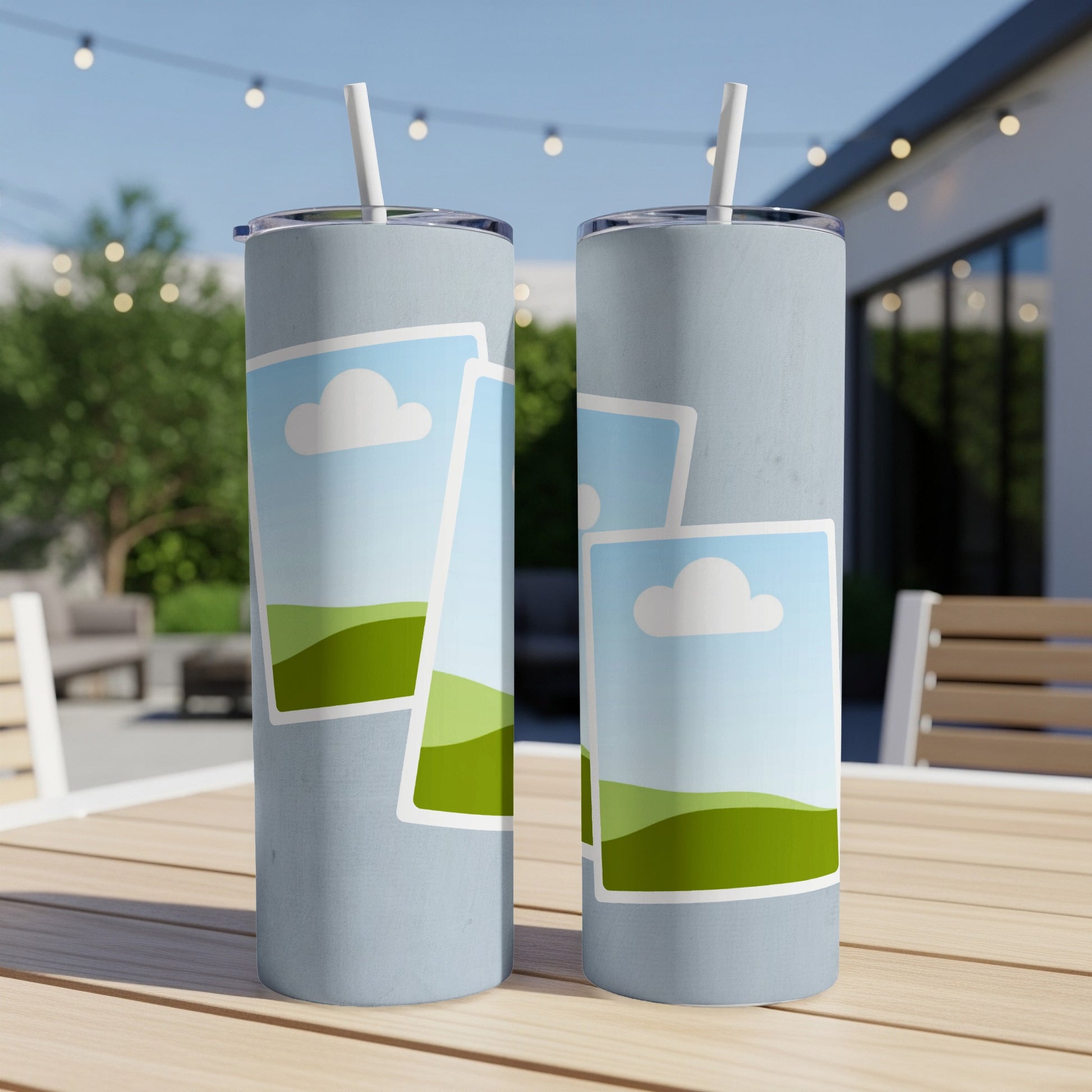 Two light blue tumblers with printed landscape photos are on a table outdoors.