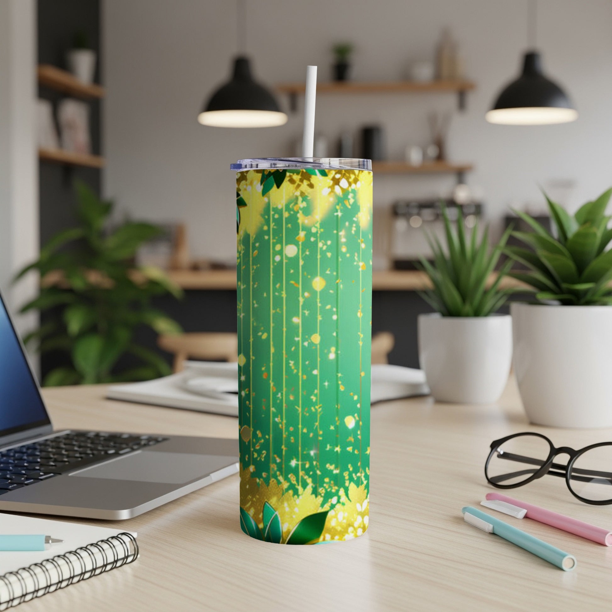 Green tumbler with gold floral and speckle pattern and white straw.