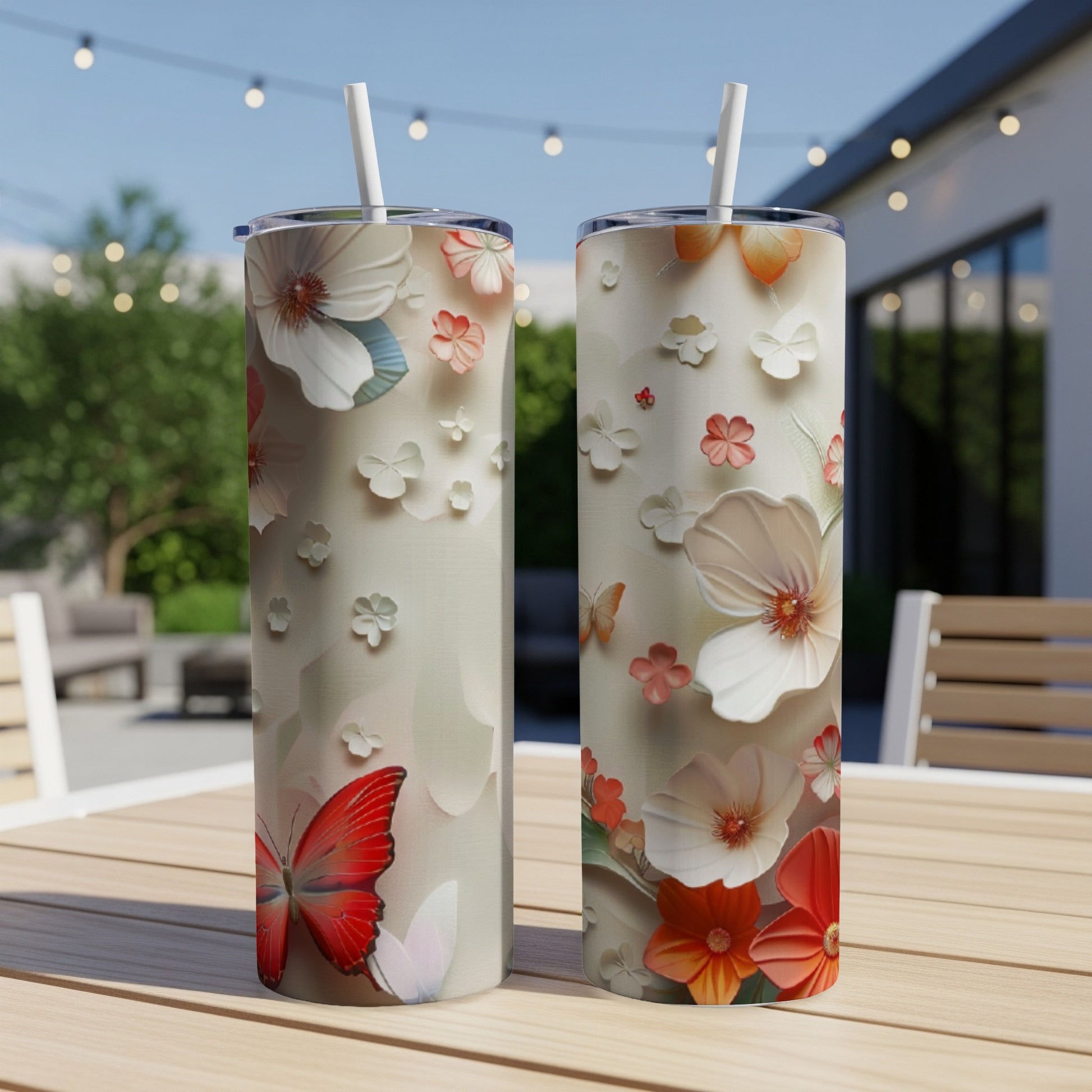 Two tall, slim tumblers with floral and butterfly designs on a wooden table.