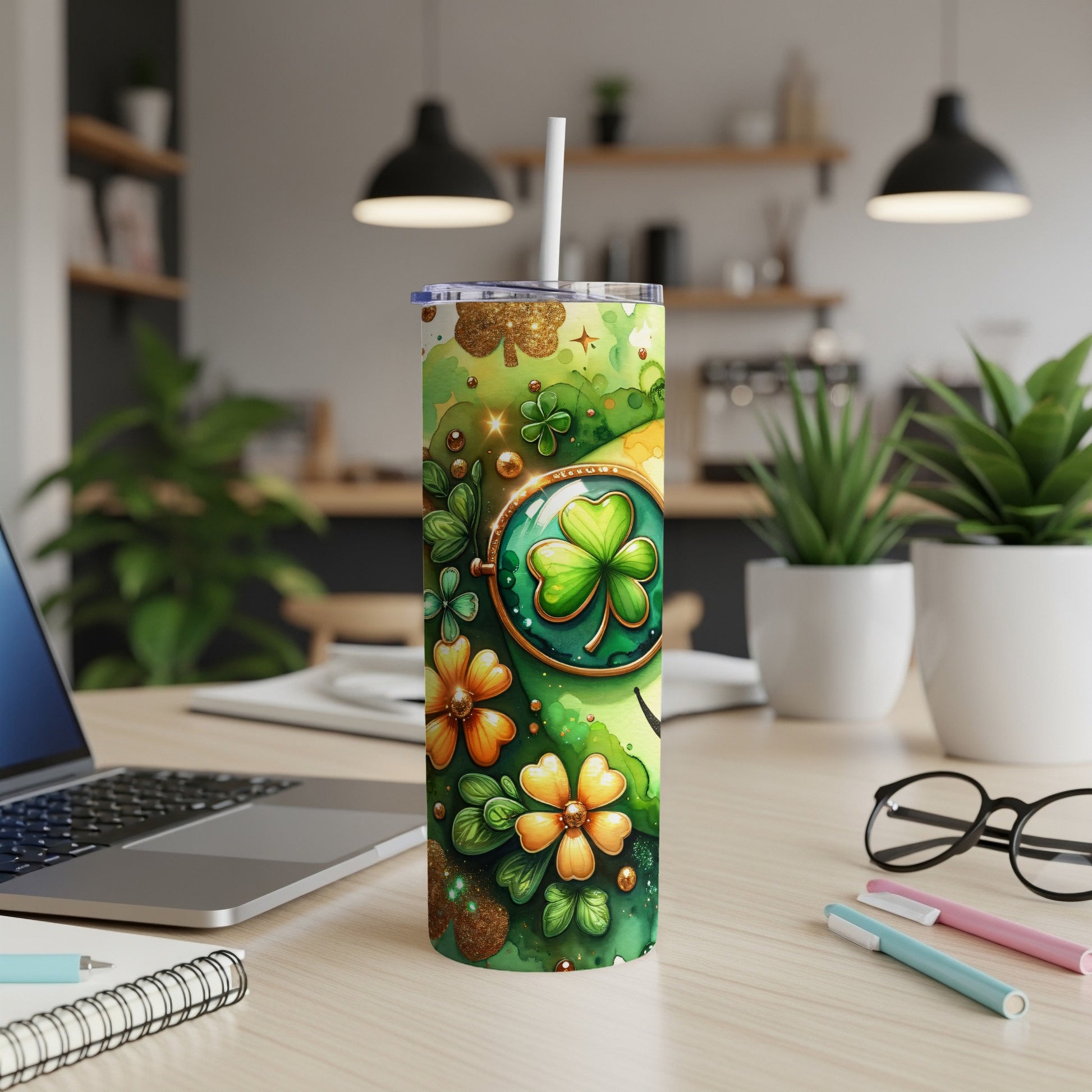 Green shamrock and flower patterned tumbler with straw on a desk.