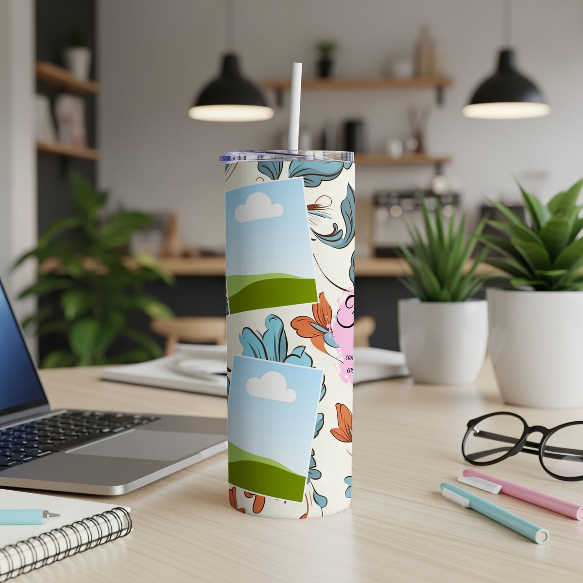 Floral patterned tumbler with photo frames and a straw on a desk.