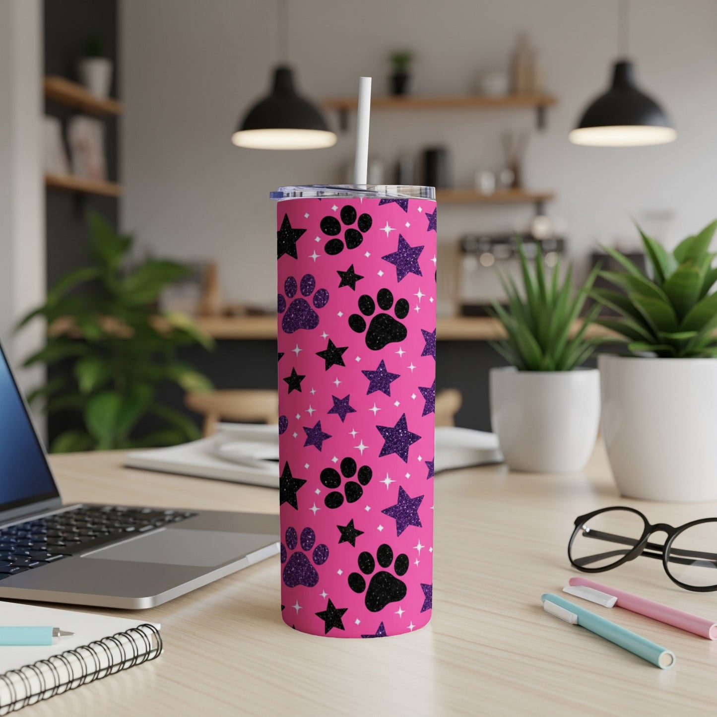 Pink tumbler with black paw prints and glitter stars, with a straw.