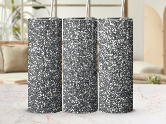 Three silver glitter tumblers with straws displayed on a marble surface.